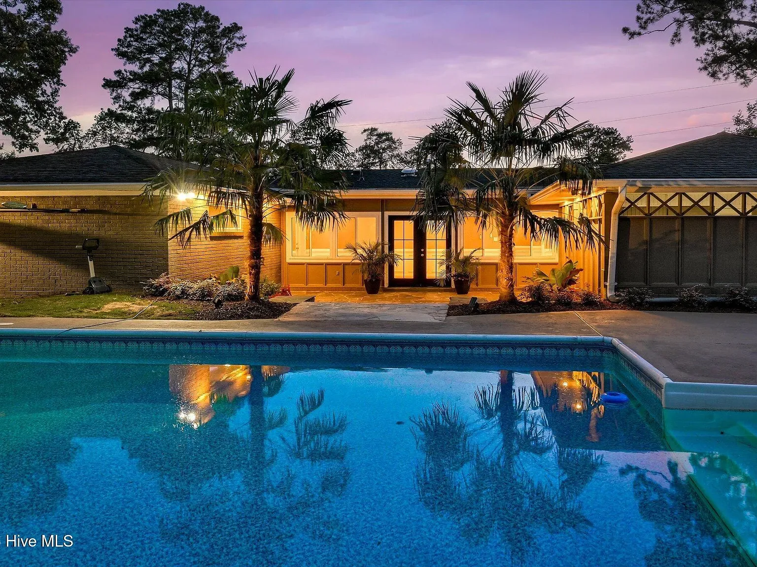 Private pool and rear elevation lit at dusk at 1135 Crestview Avenue