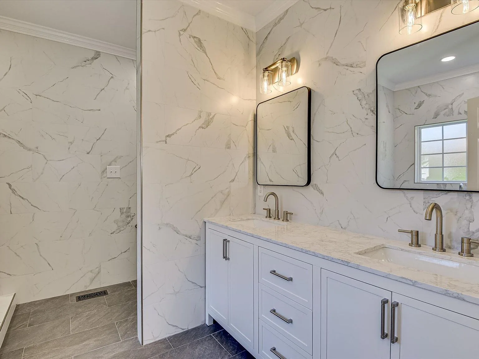 Primary bath double vanity with marble-look walls and modern fixtures at 2008 Rivershyre Drive
