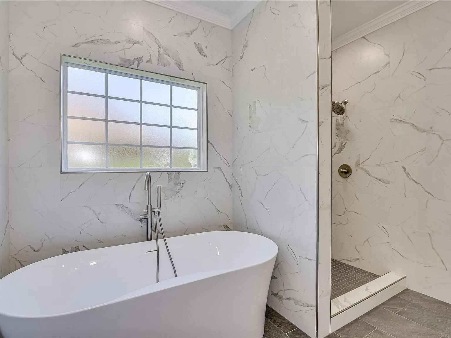 Primary bath with freestanding tub next to a marble walk-in shower at 2008 Rivershyre Drive
