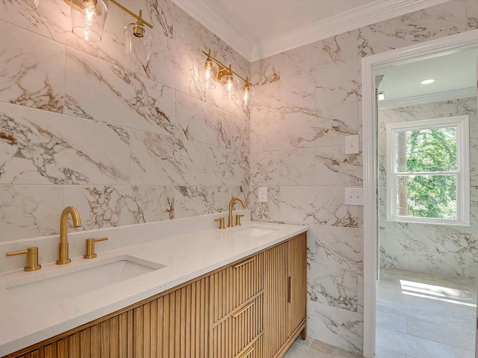Primary bath double vanity with brass fixtures and marble tile at 4 Shadowmoor Court